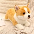 Plush Corgi stuffed toy in brown and white fur, lying in a cozy scene with soft blanket - Corgi
