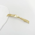 Detail einer goldenen wellenförmigen Metallhaarklammer mit poliertem Finish auf Weiß - Gold Gefaltet