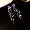 Detail view of purple rhinestone tassel earrings with V-shape design on dark surface - Black-Purple-Arrow