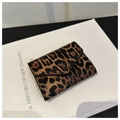 Détail d'un mini portefeuille chic à motif léopard posé sur un livre au style rétro - Marron