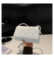 Close-up of white quilted crossbody bag featuring a knotted strap and gold metal tips - White