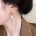 Orecchini pendenti dorati con perle a goccia indossati da una modella in stile retrò - Perla Artificiale a Goccia d'Acqua