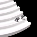 Macro shot of silver geometric earrings featuring petal details on a white wave pedestal - Triangle with Quad