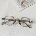 Close-up of grey transparent polygonal eyeglass frames on a white textured background - Smoke Gray