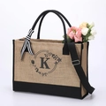 Detail of jute tote bag featuring floral letter K print and elegant ribbon decoration - Letter K