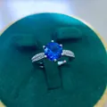 Detailed close-up of a silver ring featuring a large round blue sapphire in a six-prong setting - A9 Open Type / Blue