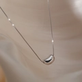 Minimalist silver bean pendant on a fine box chain over elegant beige fabric - Silver