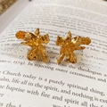 Dettaglio di orecchini dorati a forma di fiore su una pagina di un libro antico - Oro
