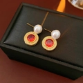 Detailaufnahme der Ohrstecker mit rotem Edelstein und Perle auf einer Geschenkbox - Roter Zirkonia Perle Stil / Echt Vergoldet Gold