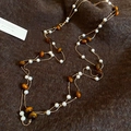Dettaglio di perle occhio di tigre e perle su catena d'oro su tessuto tweed marrone - Collana-Marrone-Bianco