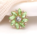 Macro shot of sun flower brooch featuring green marquise gems and white rhinestones - Green