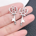 Close-up of vintage silver key charms held on a finger to show the precise product scale - Hollow Pattern Key (6699)
