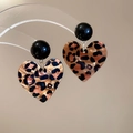 Detail of leopard print heart earrings hanging on transparent stand with silver needles - Black Bead Leopard Heart Style (30# Silver Earring Post - Brown - Heart)