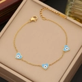 Macro shot of gold stainless steel heart bracelet with blue enamel evil eye charms - Blue