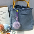 Detail of purple plush ball keychain on a denim bag with frosted chain and star hook - Purple