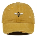 Close-up of yellow washed cotton baseball cap featuring embroidered bee and distressed holes - One Size / Orange