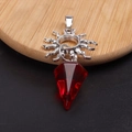 Detalle de colgante de sol plateado vintage con cristal rojo tallado en bandeja de madera - Rojo Transparente