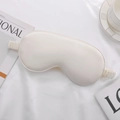 Elegant cream silk sleep mask with elastic strap shown on a cozy white fabric background - Off White