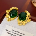 Détail de boucles d'oreilles dorées vintage avec pierres vert émeraude sur tissu - Plaqué Or Avec Vert Foncé