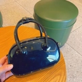 Glossy black PVC mini jelly handbag with top handles shown in a hand-held lifestyle setting - Black
