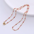 Detail of a golden chain necklace with small red beads and a secure lobster clasp - Gold - Red Beads