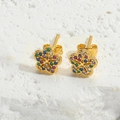 Close-up of golden flower stud earrings with colorful zircons on a textured stone base - Flower