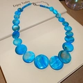 Close-up of blue iridescent shell beads on a necklace with silver lobster clasp detail - Blue