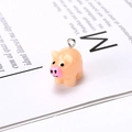 Macro shot of a pink resin pig charm with black eyes and a metal ring for DIY jewelry - Pig