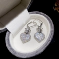 Macro shot of silver heart and crown leverback earrings with zircon stone pavé setting - Silver