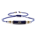 Detailed macro view of the Evil Eye charm on a blue braided bracelet with pearls - Blue