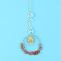Detail of sun catcher with red gravel ring, moon and sun face metal pendants - Agate
