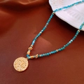 Detail of blue beaded necklace with a golden embossed eye pendant on brown satin - 22# Necklace - Gold Blue Evil Eye
