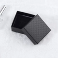 Square black jewelry gift box with textured diamond pattern lid on white plush surface - 7x7cm / Black