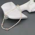 Detail of baroque pearl necklace with floral accents on a white mannequin bust - White