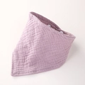 Détail d'un bavoir en mousseline lavande montrant la texture crêpée et le bouton pression - Violet