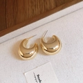 Vue rapprochée de boucles d'oreilles en C dorées sur un tissu à texture naturelle - Grande Forme J (Tige en Acier - Or)