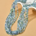 Close-up of multi-colored 3mm faceted crystal beads in a white ceramic bowl for DIY jewelry - Blue Green AB