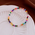 Macro di un braccialetto di perline colorate in pietre dure in una ciotola di ceramica - Bracciale con Perline di Pietra Colorata