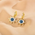 Detail von goldenen Evil-Eye-Ohrringen mit blauen Inlays und weißen Steinen auf Stoff - Strass-Stil