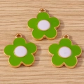 Three green daisy flower charms with gold edges on a rustic wooden background - Green