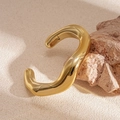Dettaglio macro di un bracciale dorato lucido con linee organiche su pietra naturale - Oro