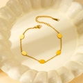 Detail of gold stainless steel bracelet with five oval charms on a textured white plate - Gold Oval Bracelet
