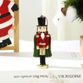 Close-up of glittery red and green nutcracker soldier ornament hanging on a Christmas tree - Nutcracker Soldier with Cloak
