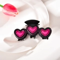 Détail d'une pince à cheveux en résine noire avec cœurs roses sur un plateau blanc - 10cm / Noir et Rose Fraise