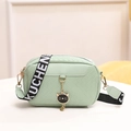 Mint green crossbody bag with textured pattern and a cat charm on a wide lettered strap - Green