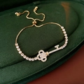 Macro shot of gold-plated key pendant bracelet with micro-pave zircons on green velvet - Gold