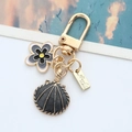 Golden alloy keychain featuring a black shell pendant and small floral charm - Black Shell
