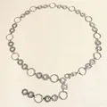 Detail of silver metal chain belt with smooth rings, hammered texture, and lobster clasp - Silver