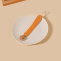 Détail de l'attache-tétine en coton orange vif sur une assiette en céramique blanche - Style Orange (10)