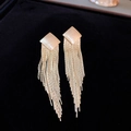 Detailopname van gouden kwastoorbellen met geborstelde ruitvormige studs op zwart fluweel - Gouden Ruit Kwastje